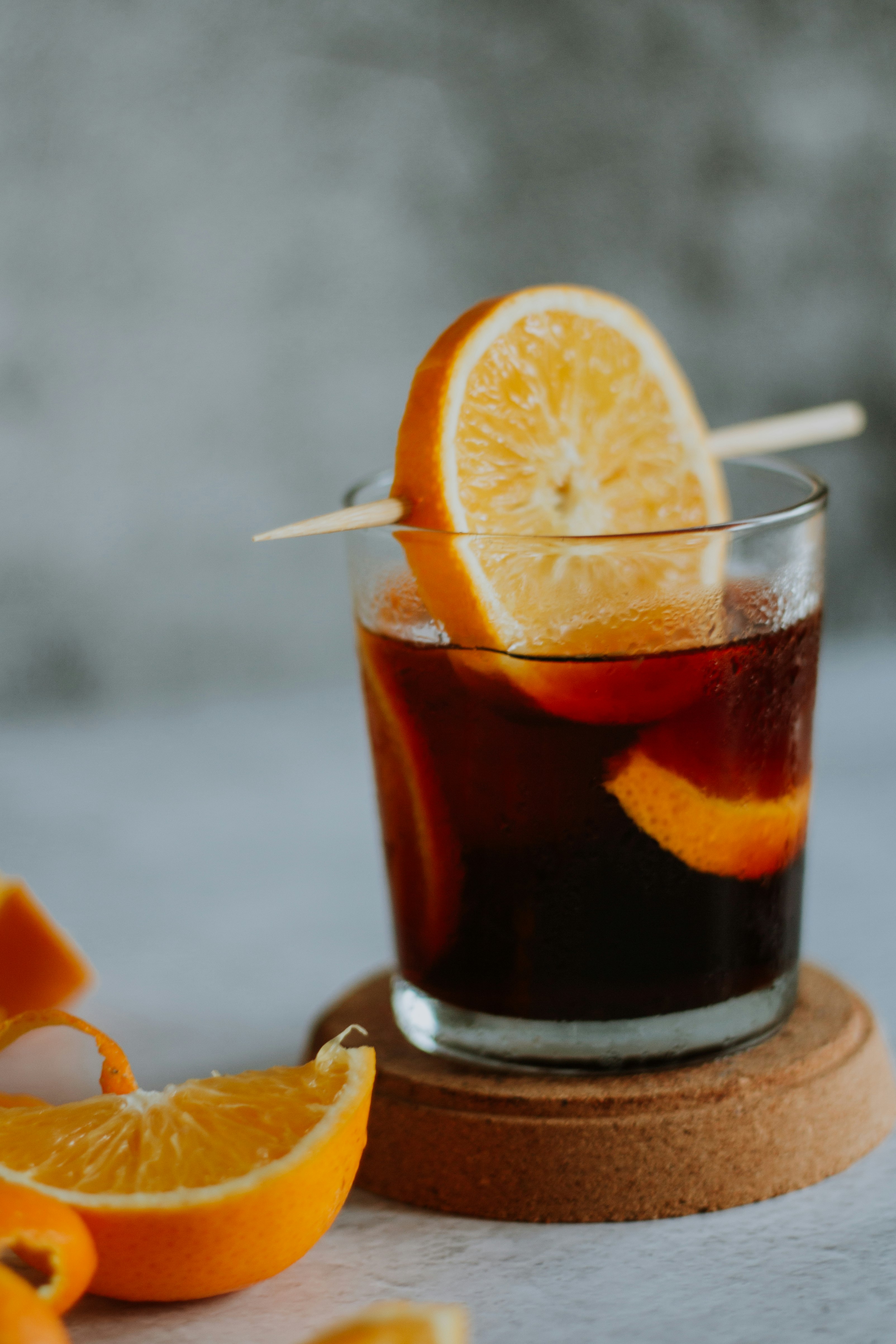 clear drinking glass with brown liquid and sliced orange fruit